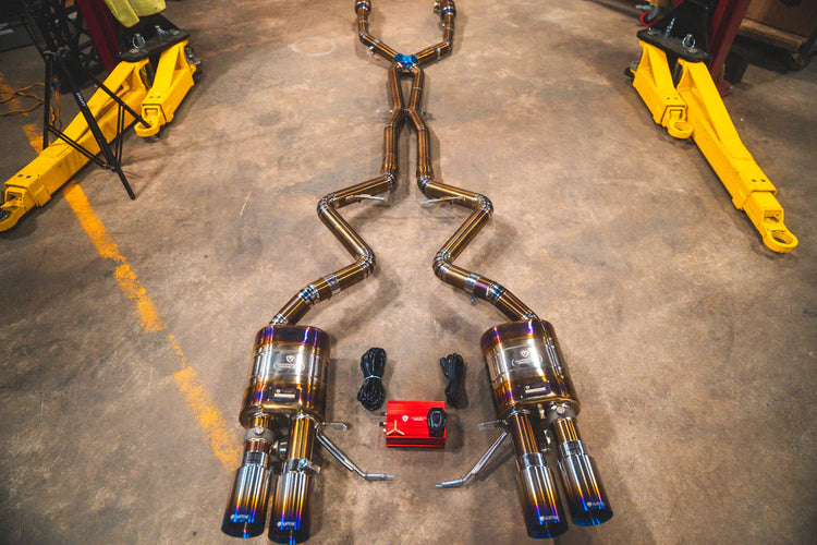 A wide overview from the top of Valvetronic Designs Titanium Valved Sport Exhaust System on the ground with all its parts (for BMW M3 E9X).