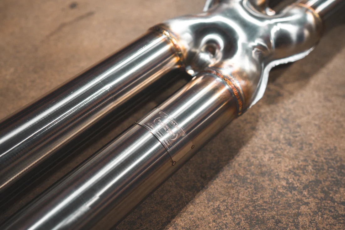 A close up view of Valvetronic Designs Valved Sport Exhaust System's pipes on the ground (Alpina B6 / BMW 650i).