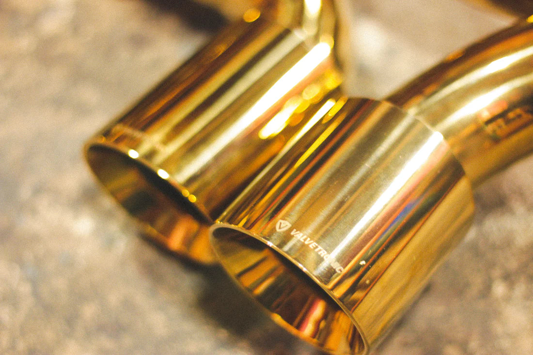 A close up view of Valvetronic Designs Valved Sport Exhaust System's exhaust tips on the ground (for Porsche 911 Carrera / S / GTS, Targa 4 / S / GTS).