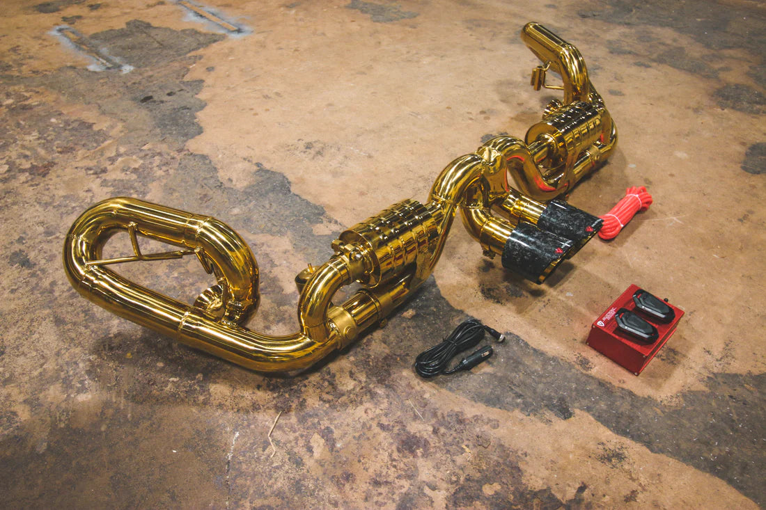 A side overview of Valvetronic Designs Valved Sport Exhaust System with valve controllers and wires on the ground (for Porsche 991 GT3 / RS).