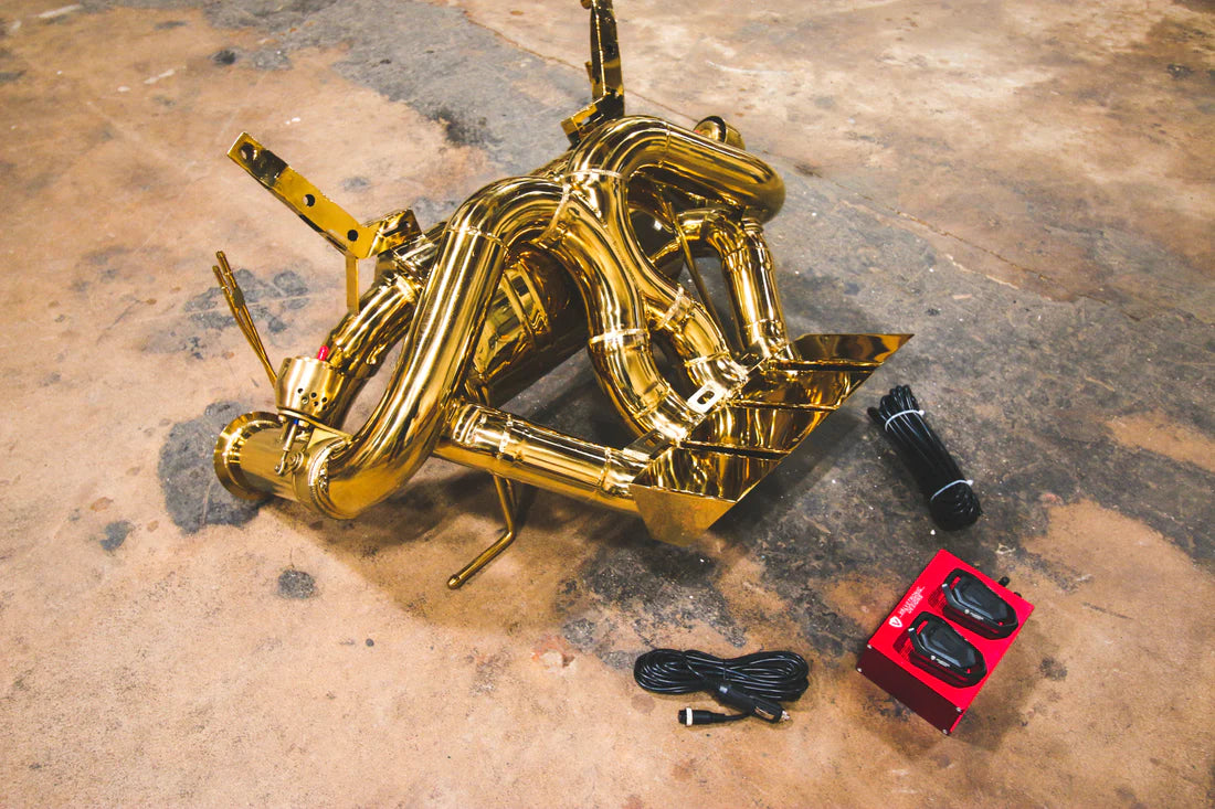 A side close overview of Valvetronic Designs Valved Sport Exhaust System with valve controllers on the ground (for Lamborghini Aventador LP700 / SV).