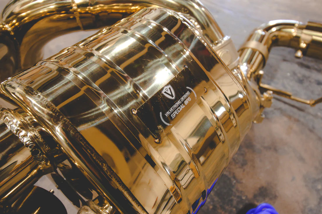 A side close up view of Valvetronic Designs Valved Sport Exhaust System's muffler on the ground (for Mclaren 570S / 620R).