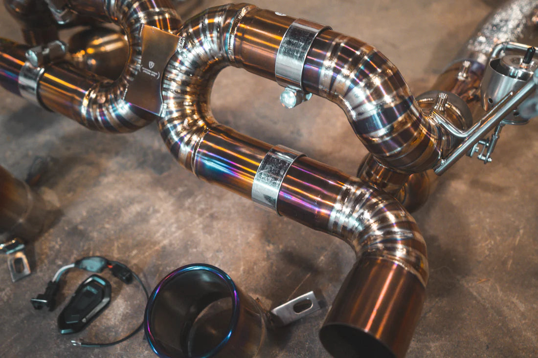 A close up view of Valvetronic Designs Valved Sport Exhaust System's pipes on the ground (for Ferrari F8).