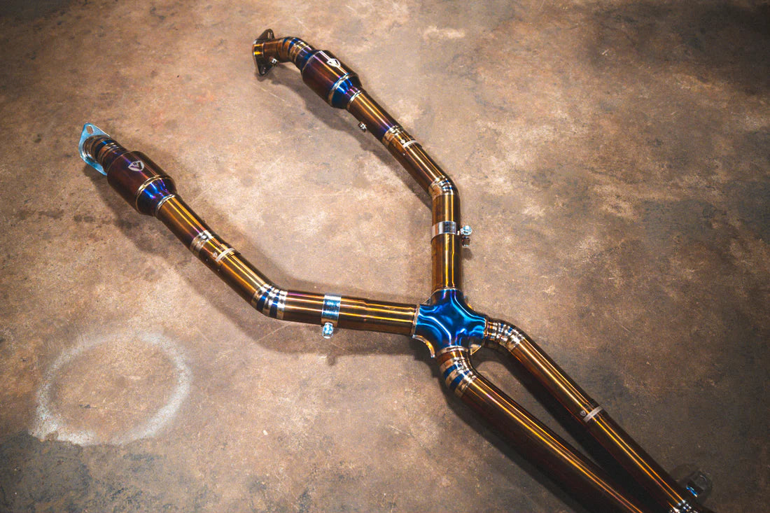 A wide view of Valvetronic Designs Titanium Valved Sport Exhaust System's pipes on the ground (for BMW M3 E9X).