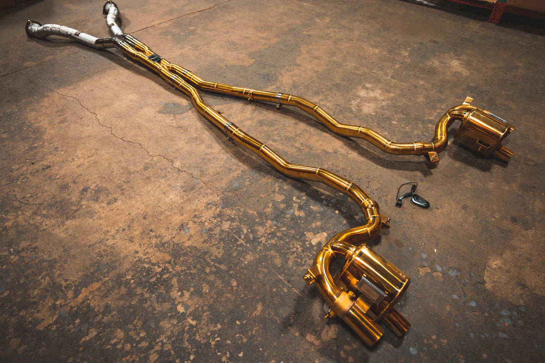 A wide overview from the side of Valvetronic Designs Ferrari Valved Exhaust system with free flow front pipes and valve controller on the ground (for GTC4 Lusso).