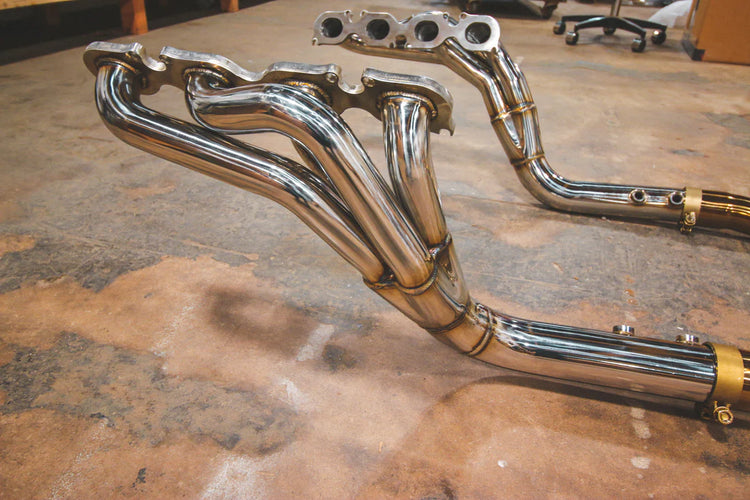 A side overview of Valvetronic Designs Free Flow Race Headers on the ground (for Mercedes W204 C63 AMG).