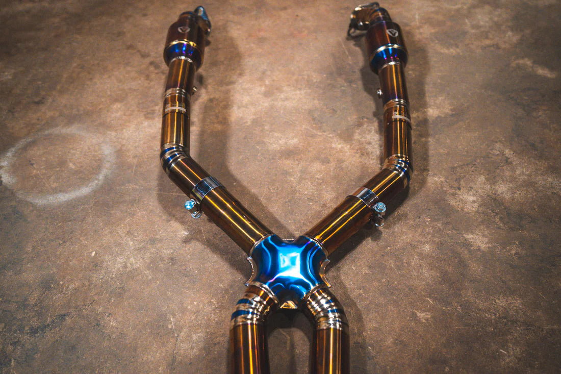 A close up view from the top of Valvetronic Designs Titanium Valved Sport Exhaust System's pipes on the ground (for BMW M3 E9X).