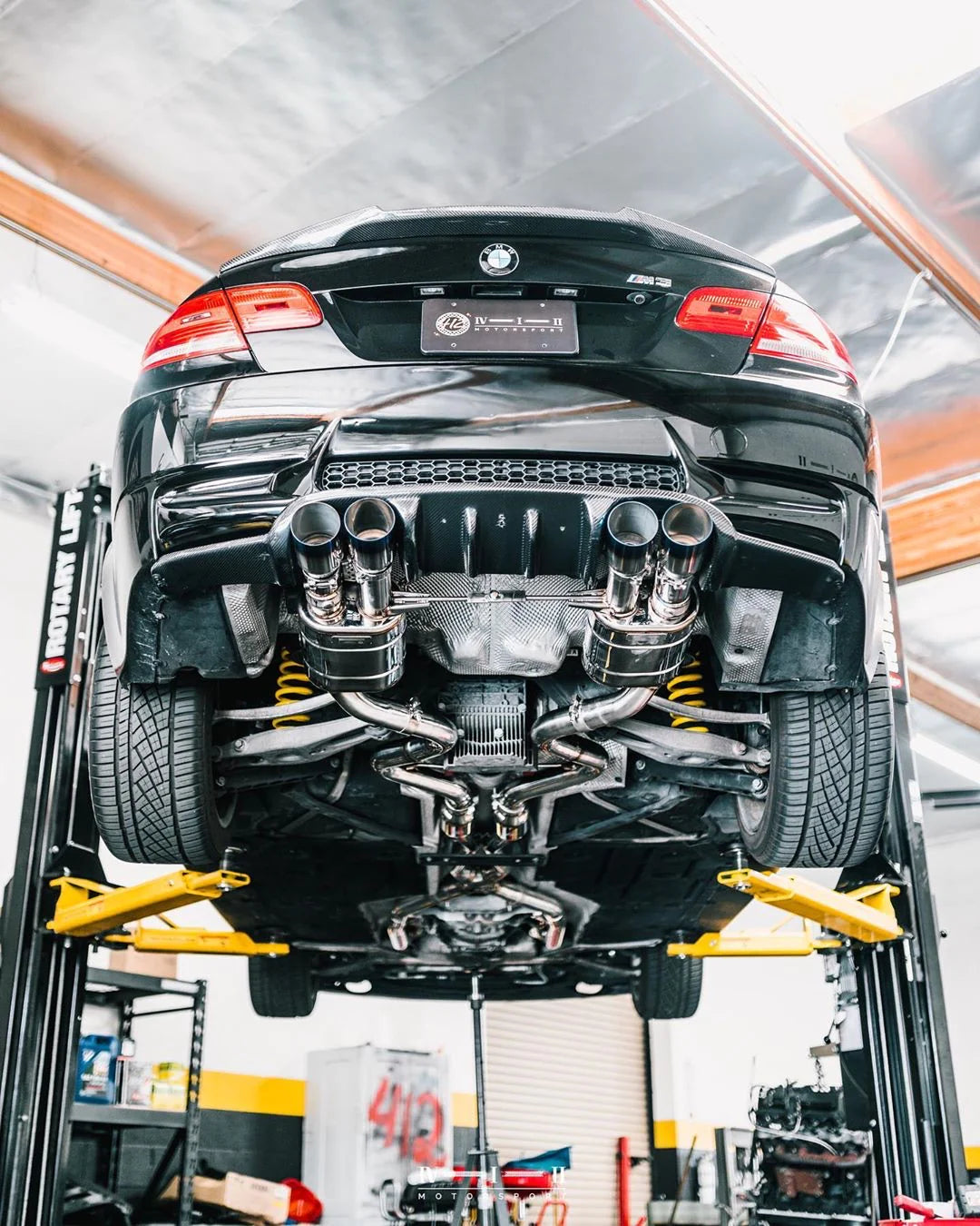 A wide view of Valvetronic Designs Midpipe V2 fitted on a lifted car (for BMW M3 E9x).