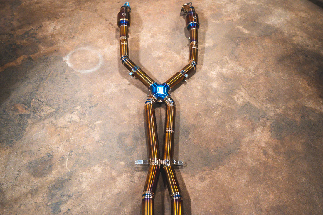 A wide angle view of Valvetronic Designs Titanium Valved Sport Exhaust System's pipes on the ground (for BMW M3 E9X).