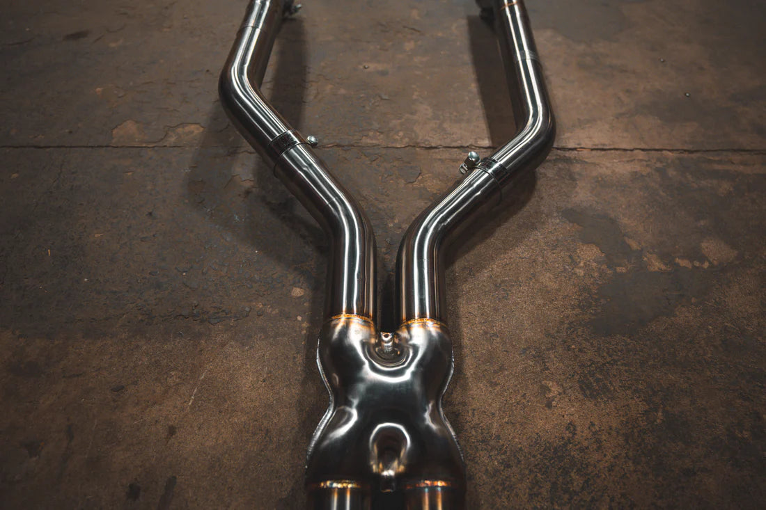 A close up view of Valvetronic Designs Valved Sport Exhaust System's pipes on the ground (Alpina B6 / BMW 650i).