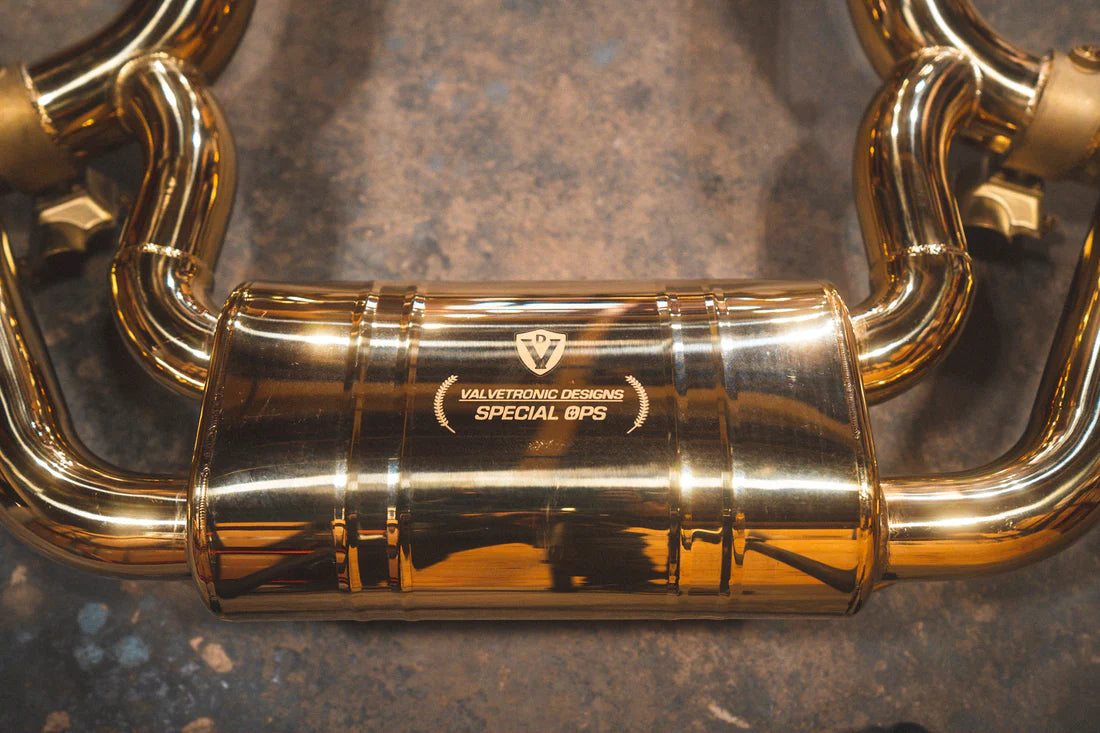 A close up view of Valvetronic Designs Valved Sport Exhaust system's muffler and pipes on the ground (for Mercedes AMG GT).