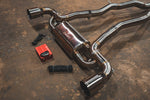A side close overview of Valvetronic Designs Brushed Valved Sport Exhaust System with valve controllers and wires on the ground (for Toyota Supra A90 / A91).