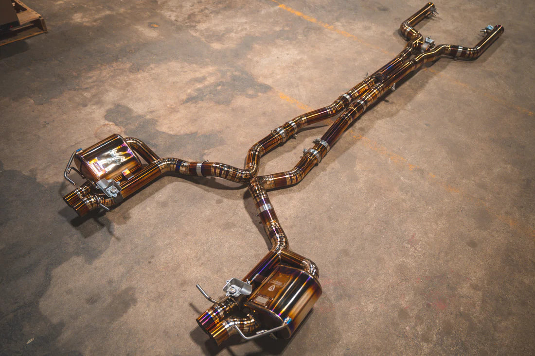 A side overview of Valvetronic Designs Titanium Valved Sport Exhaust System on the ground (for Mercedes W205 C63 / C63s).