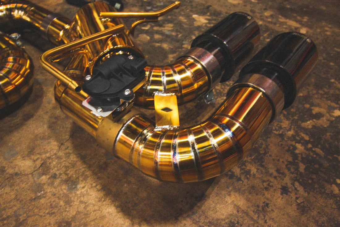 A close up view of Valvetronic Designs Valved Sport Exhaust System's exhaust tips on the ground (for Chevrolet Corvette C8).