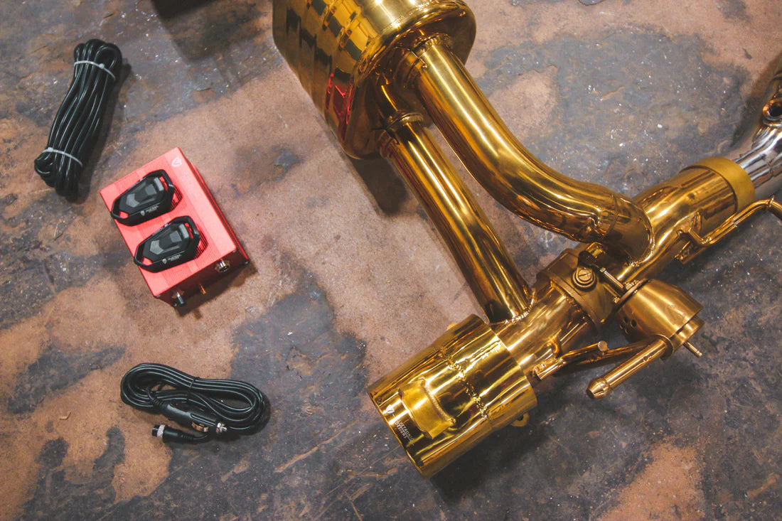 A close up view of Valvetronic Designs Valved Sport Exhaust System with valve controllers on the ground (for Ferrari 488 GTB and Pista).