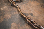 A wide view of Valvetronic Designs Equal Length Valved Sport Exhaust System's pipes on the ground (for BMW M3 F80, M4 F82, M4 F83).
