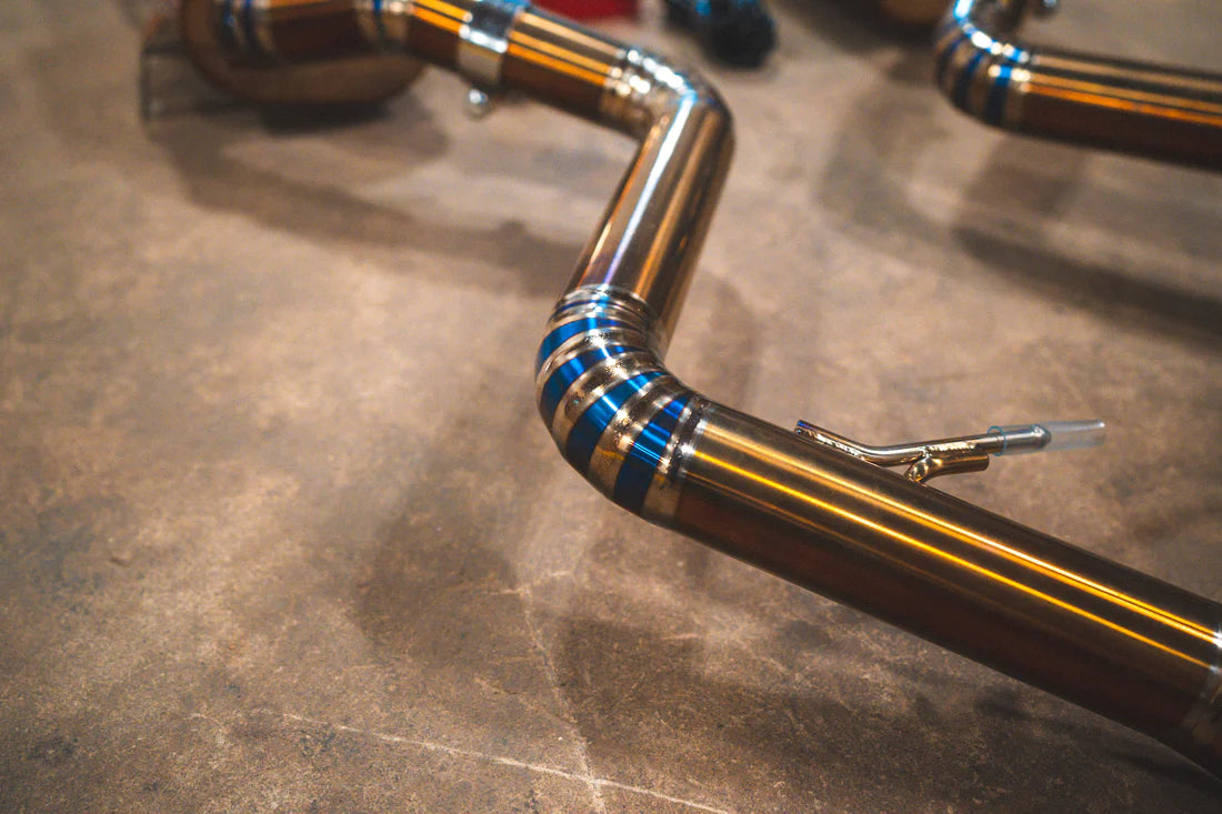 A close up view of part of Valvetronic Designs Titanium Valved Sport Exhaust System's pipes on the ground (for BMW M3 E9X).