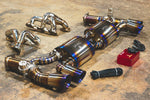 A side overview of Valvetronic Designs Valved Race Exhaust System with valve controllers and free flow headers on the ground (for Porsche 991 Turbo / Turbo S).