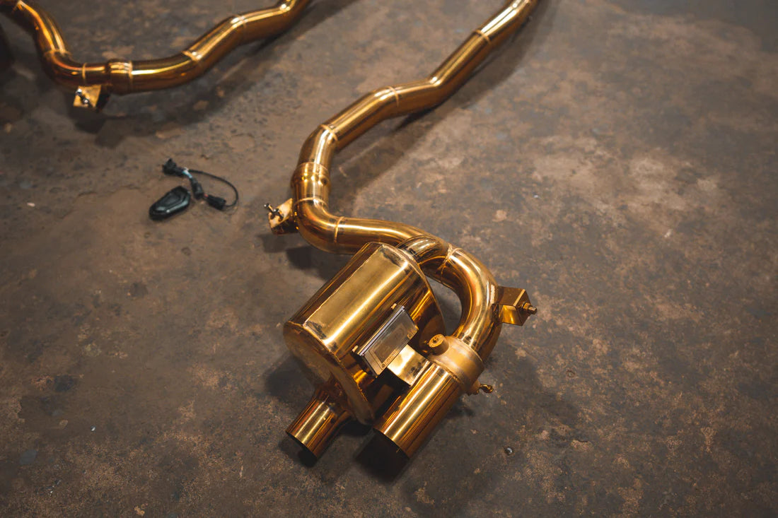 A close up view of Valvetronic Designs Ferrari Valved Exhaust system's pipes and muffler on the ground (for GTC4 Lusso)