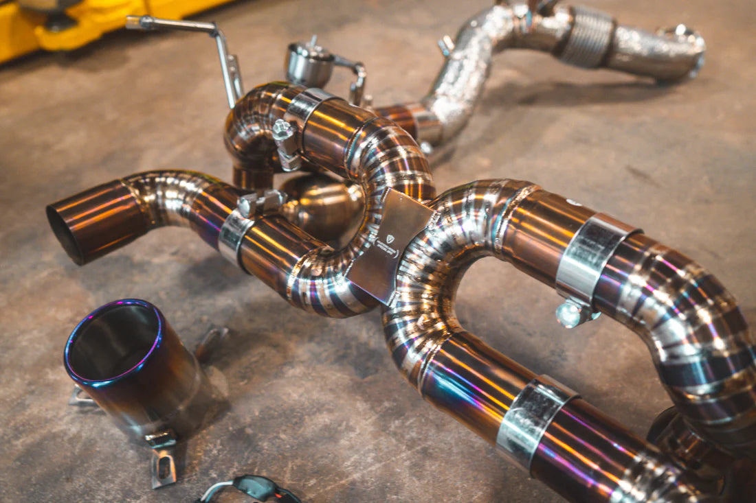 A close up view of Valvetronic Designs Valved Sport Exhaust System with free flow front pipes on the ground (for Ferrari F8).