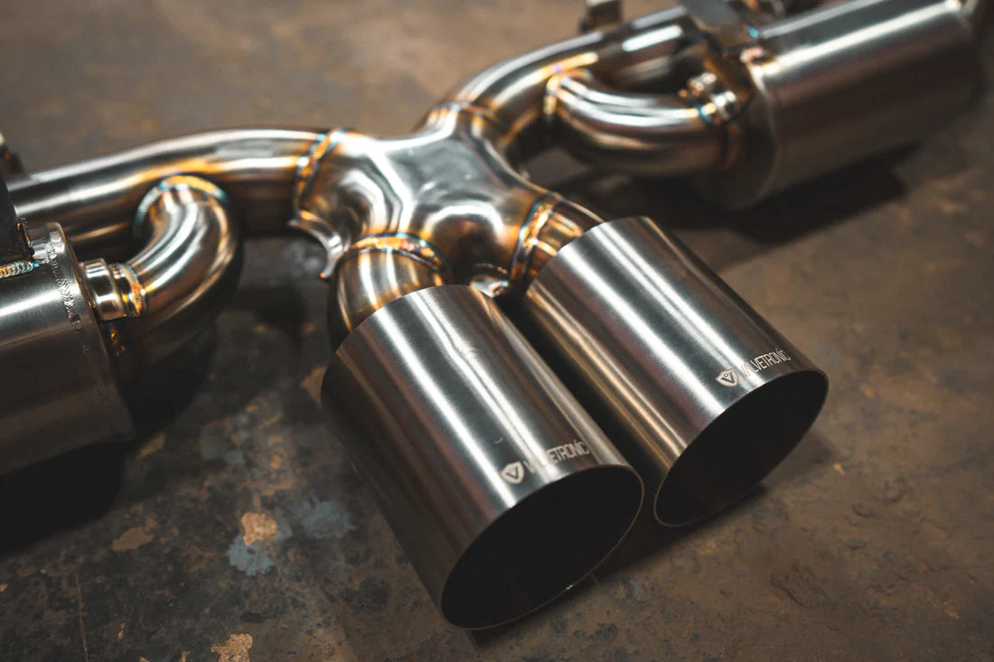 A close overview of Valvetronic Designs Valved Sport Exhaust System's exhaust tips on the ground (for Porsche 992 GT3/ RS).