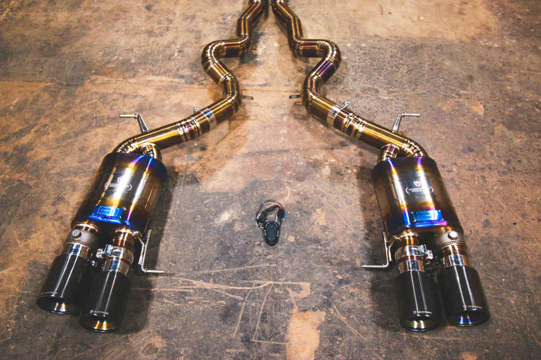 A wide overview of Valvetronic Designs Titanium Grade 5 Valved Sport Exhaust System with Black exhaust tips on the ground (for BMW F10 M5 / F12 M6 / F06 M6).