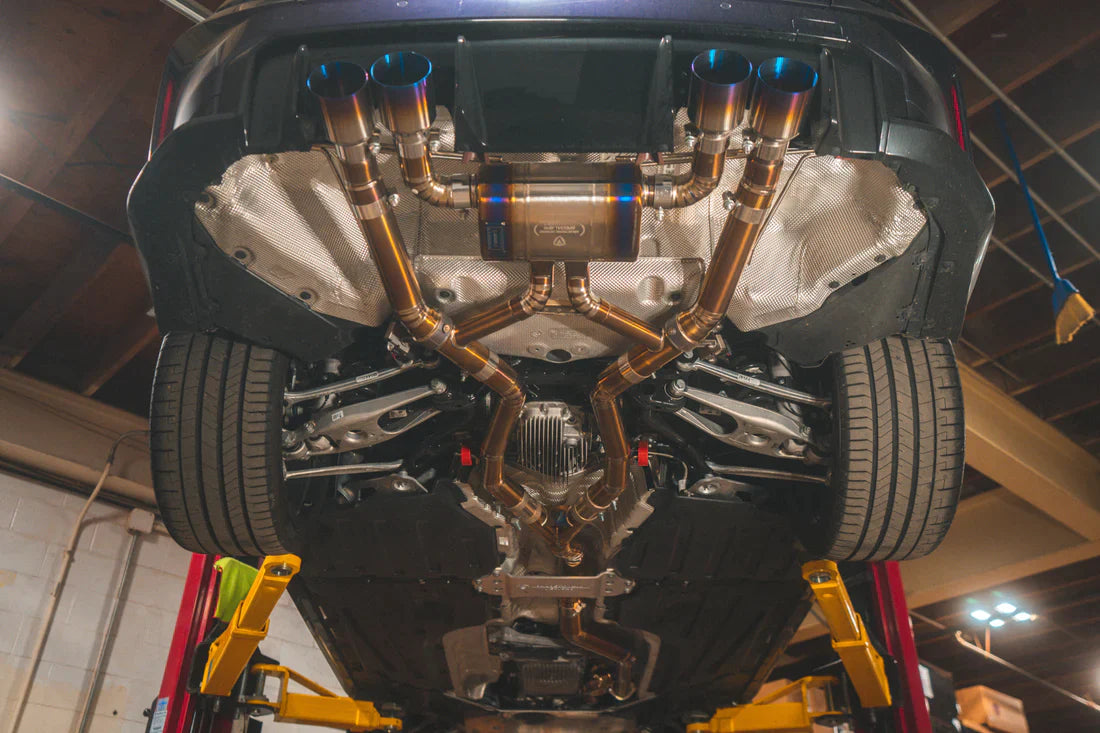 A close view of Valvetronic Designs Valved Sport Exhaust System with fitted on a lifted car from beneath (for BMW G8x M3 / M4). 