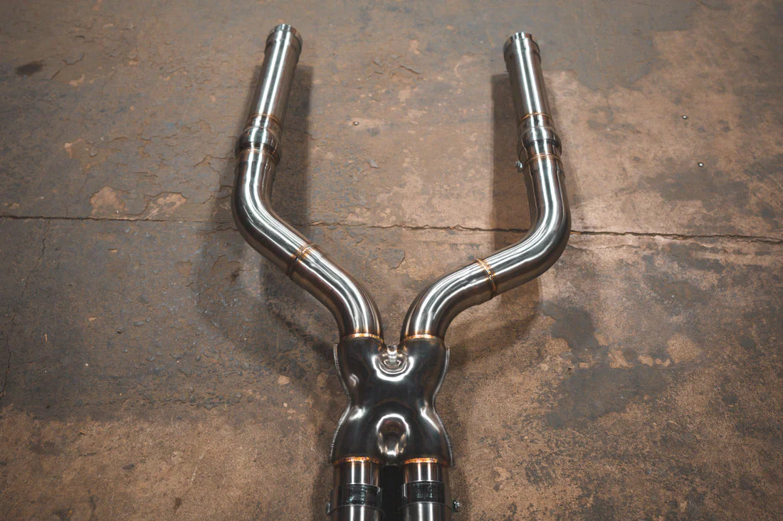 A close view of Valvetronic Designs Valved Sport Exhaust System's pipes on the ground (for BMW F90 M5). 