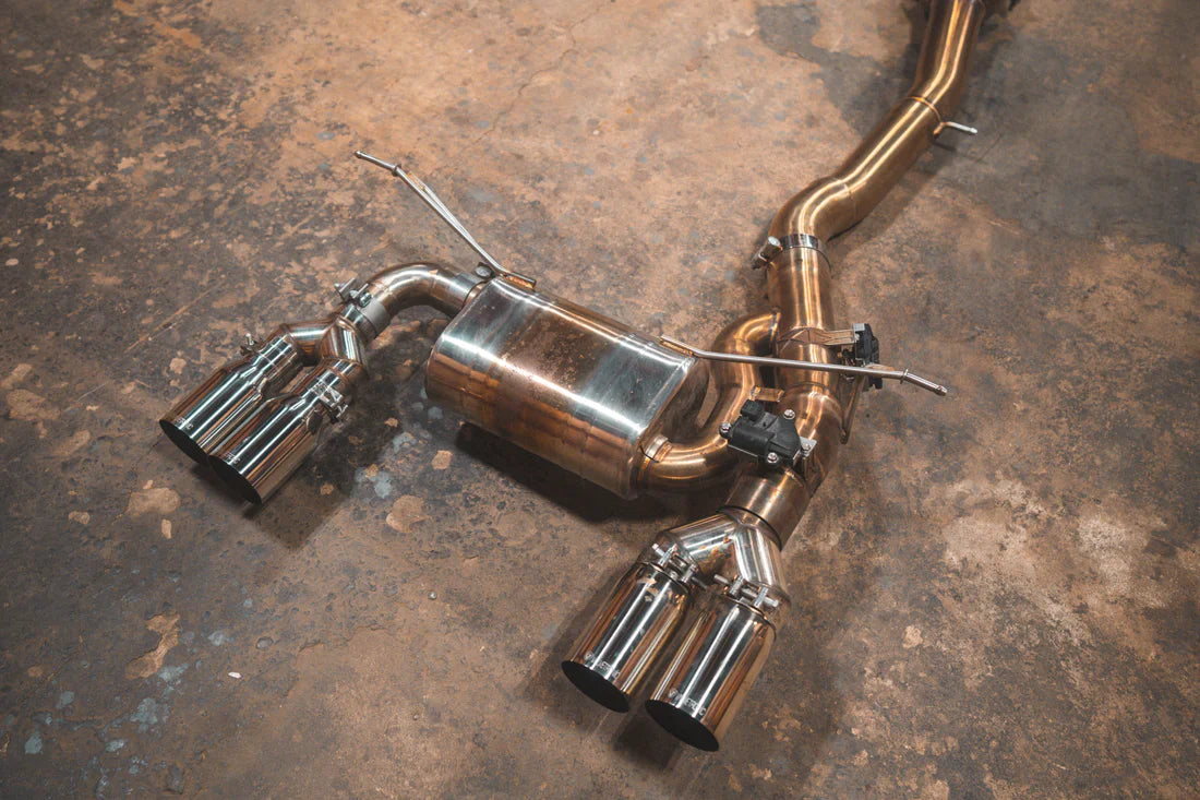 A close up view of Valvetronic Designs Equal Length Valved Sport Exhaust System with Chrome exhaust tips on the ground (for BMW M3 F80, M4 F82, M4 F83).