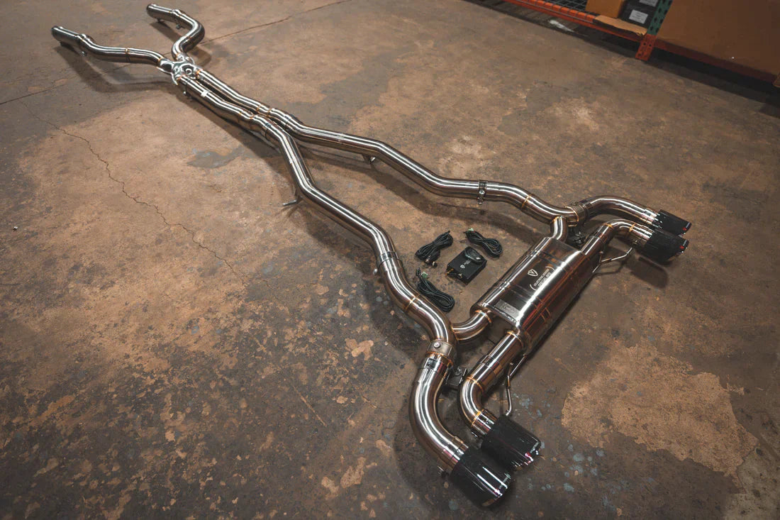 A wide side view of Valvetronic Designs Valved Sport Exhaust System on the ground (for BMW F90 M5).