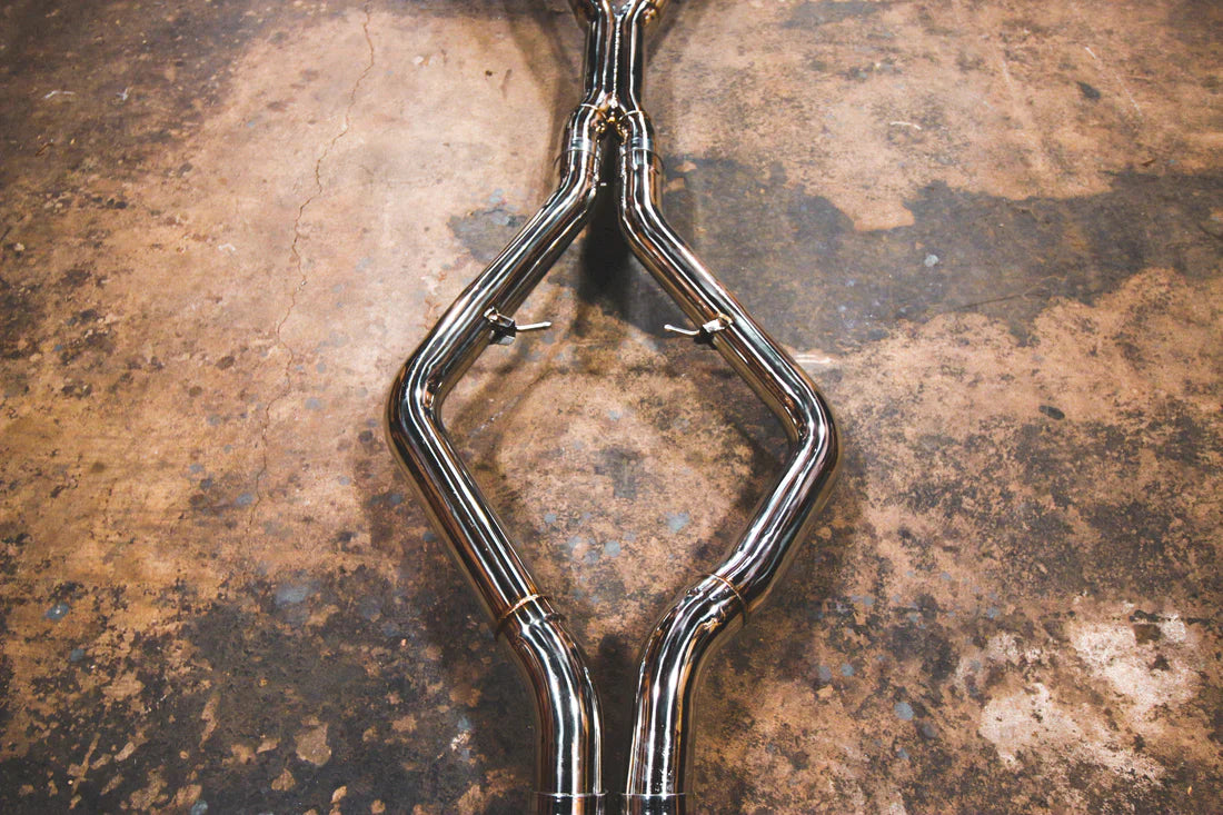 A close up view of Valvetronic Designs Valved Sport Exhaust System's pipes on the ground (for BMW X5M F85 / X6M F86).