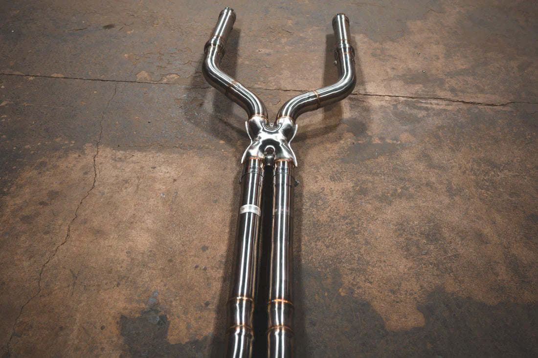 A wide view of Valvetronic Designs Valved Sport Exhaust System's pipes on the ground (for BMW F90 M5). 