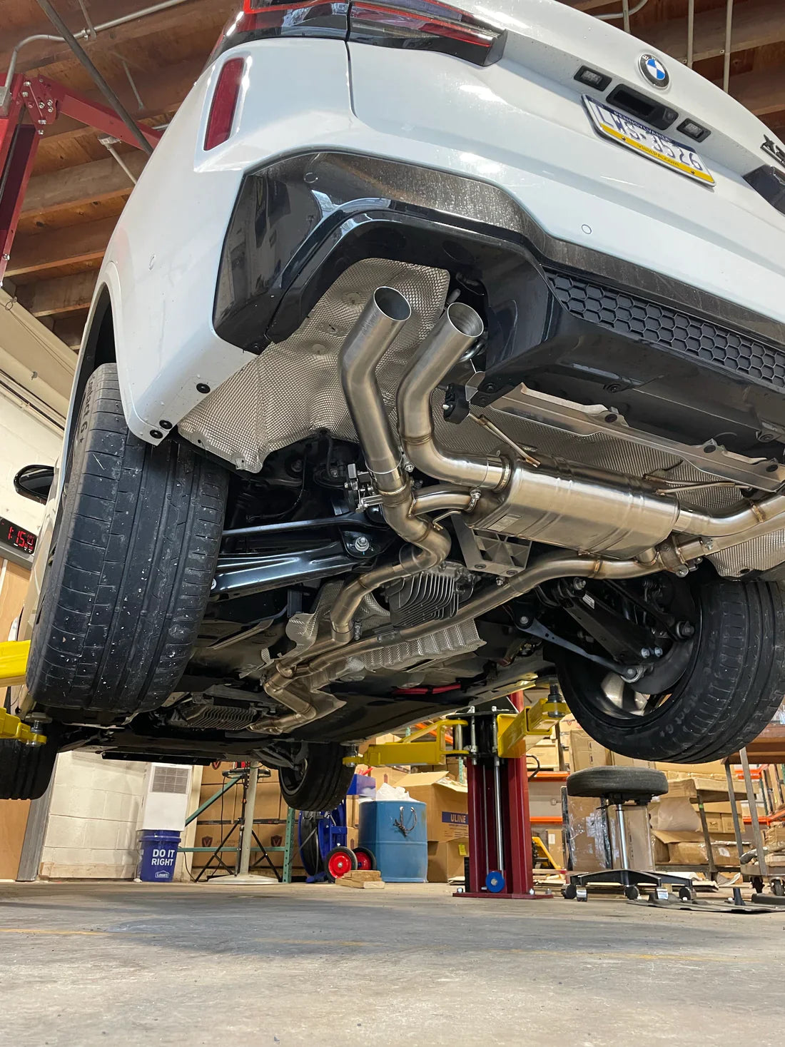 A wide view of Valvetronic Designs Valved Sport Exhaust System fitted on a lifted car from behind (for BMW X3M F97 / X4M F98).