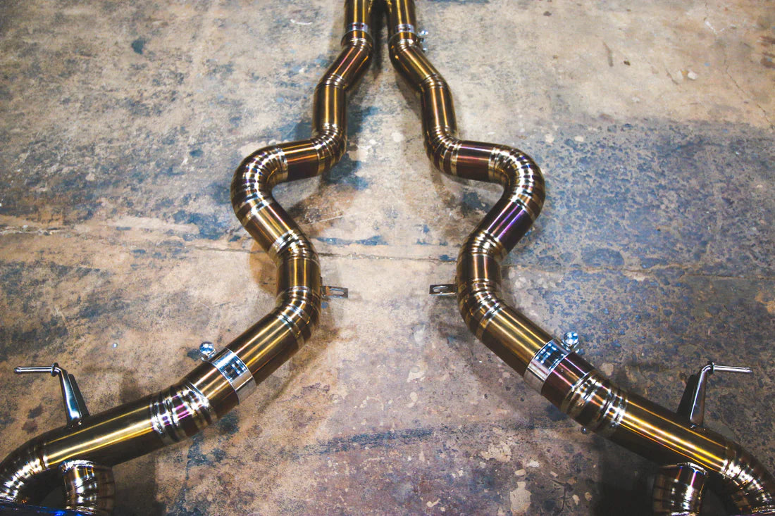 A wide overview of Valvetronic Designs Titanium Grade 5 Valved Sport Exhaust System's pipes on the ground (for BMW F10 M5 / F12 M6 / F06 M6).