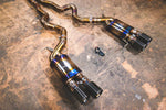 A close overview of Valvetronic Designs Titanium Grade 5 Valved Sport Exhaust System with Black exhaust tips on the ground (for BMW F10 M5 / F12 M6 / F06 M6).