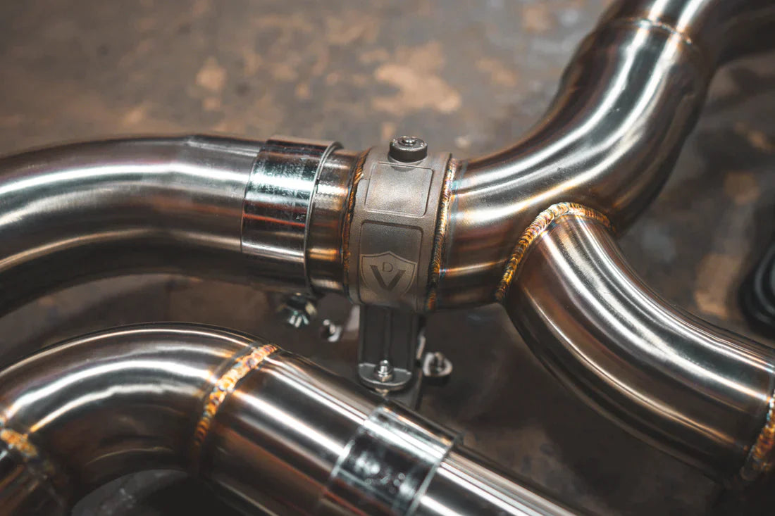 A close view of Valvetronic Designs Valved Sport Exhaust System's pipes on the ground (for BMW F90 M5). 