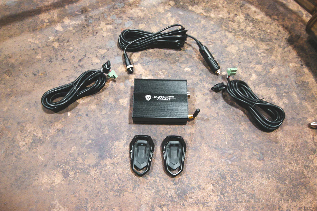 A close up view of Valvetronic Designs Valved Sport Exhaust System's valve controller and wires on the ground (for BMW X5M F85 / X6M F86).