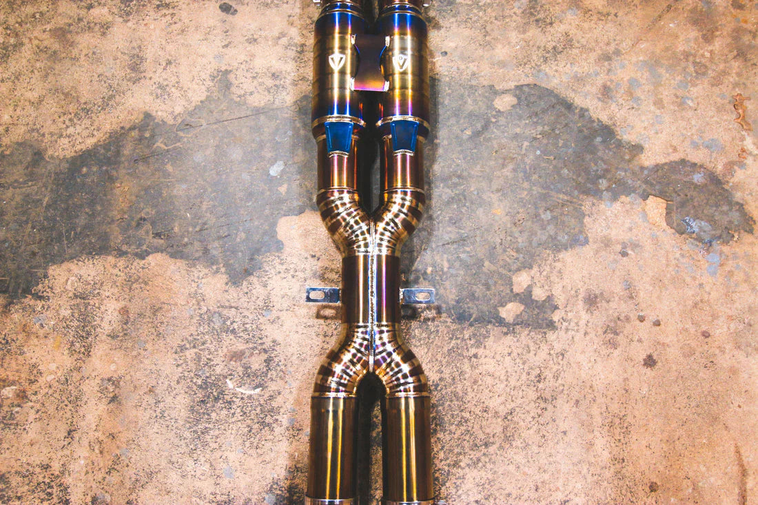 A close overview of Valvetronic Designs Titanium Grade 5 Valved Sport Exhaust System's pipes on the ground (for BMW F10 M5 / F12 M6 / F06 M6).