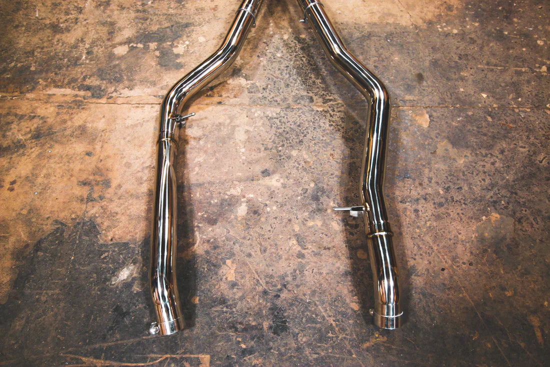 A close up view of Valvetronic Designs Valved Sport Exhaust System's pipes on the ground (for BMW X5M F85 / X6M F86).
