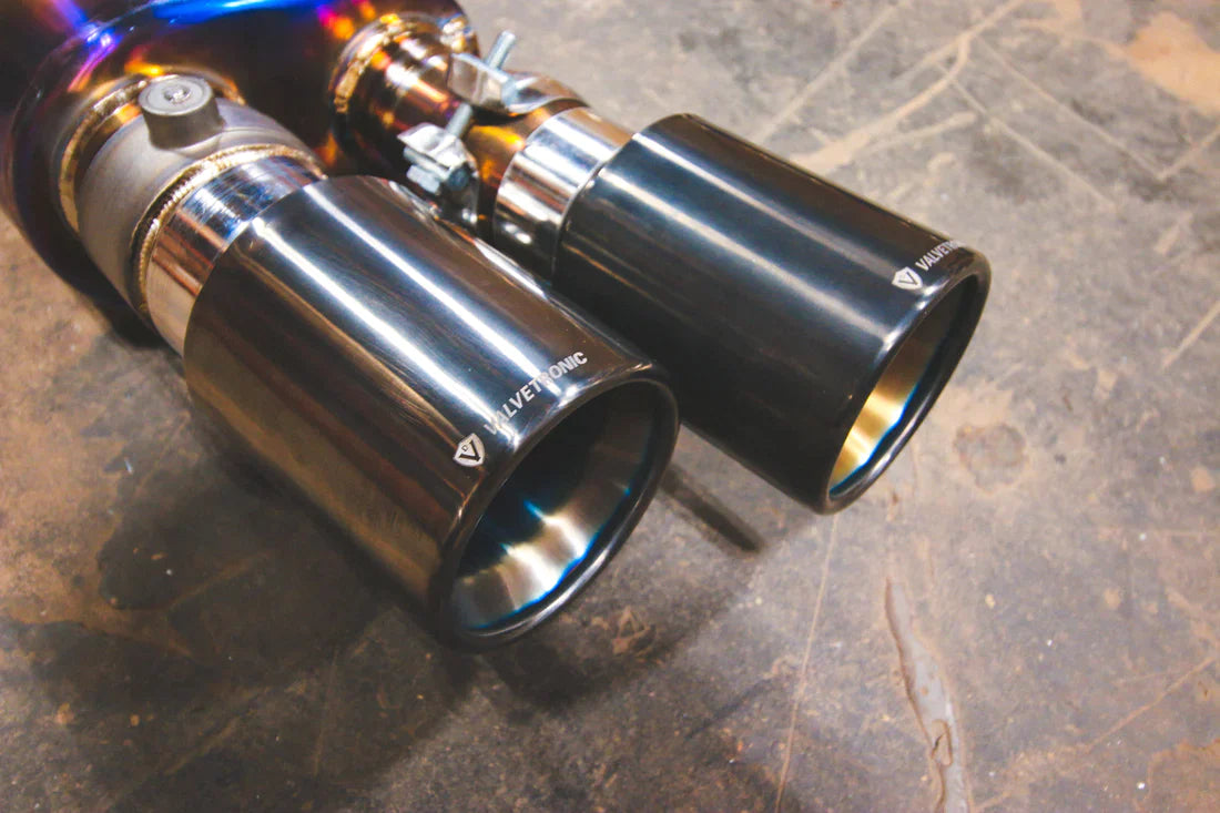 A close overview of Valvetronic Designs Titanium Grade 5 Valved Sport Exhaust System's chrome exhaust tips on the ground (for BMW F10 M5 / F12 M6 / F06 M6).
