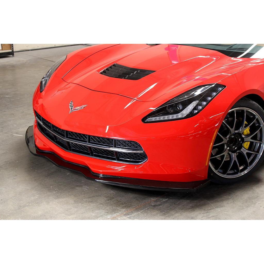 Black carbon fiber front airdam splitter installed on red Corvette, extends below front bumper with aggressive aerodynamic design - APR Performance front airdam for Chevrolet C7 Corvette Corvette Z06