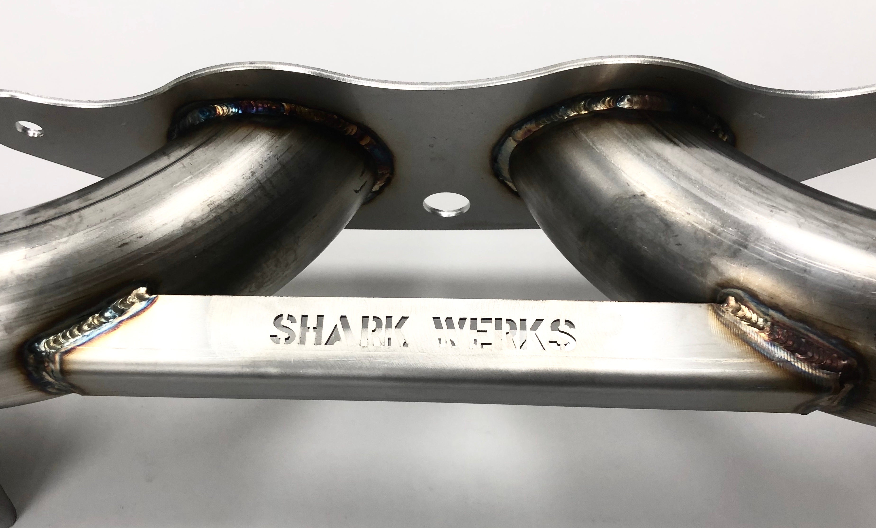 A close up view of a part of Shark Werks Sport Exhaust for Porsche 991 GT3 / RS and 991.2 GT3 / R showing Shark Works logo