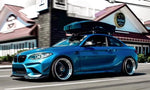 A side wide view of AUTOTECKNIC FRONT BUMPER DRY CARBON CANARD SET - BMW F87 M2 | M2 Competition 2016+ fitted on a blue car
