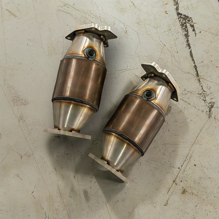 A top view of Milltek HJS Hi-Flow Sports Cats w/ No Heat Wrap for Chevrolet Corvette C8 Z06 5.5L V8 2023-2025 laying on beige titled floor