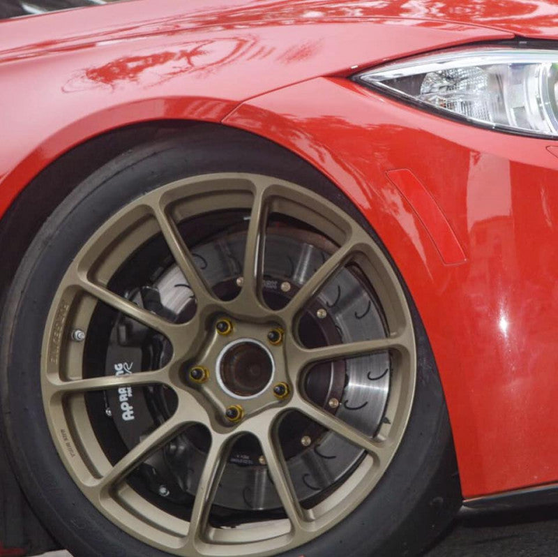 A close up view of the front of a red car and its wheel fitted with AP Racing by Essex Radi-CAL ENP Competition Brake Kit (Front CP9449/340mm)- ND Mazda Miata & Fiat 124 Spider