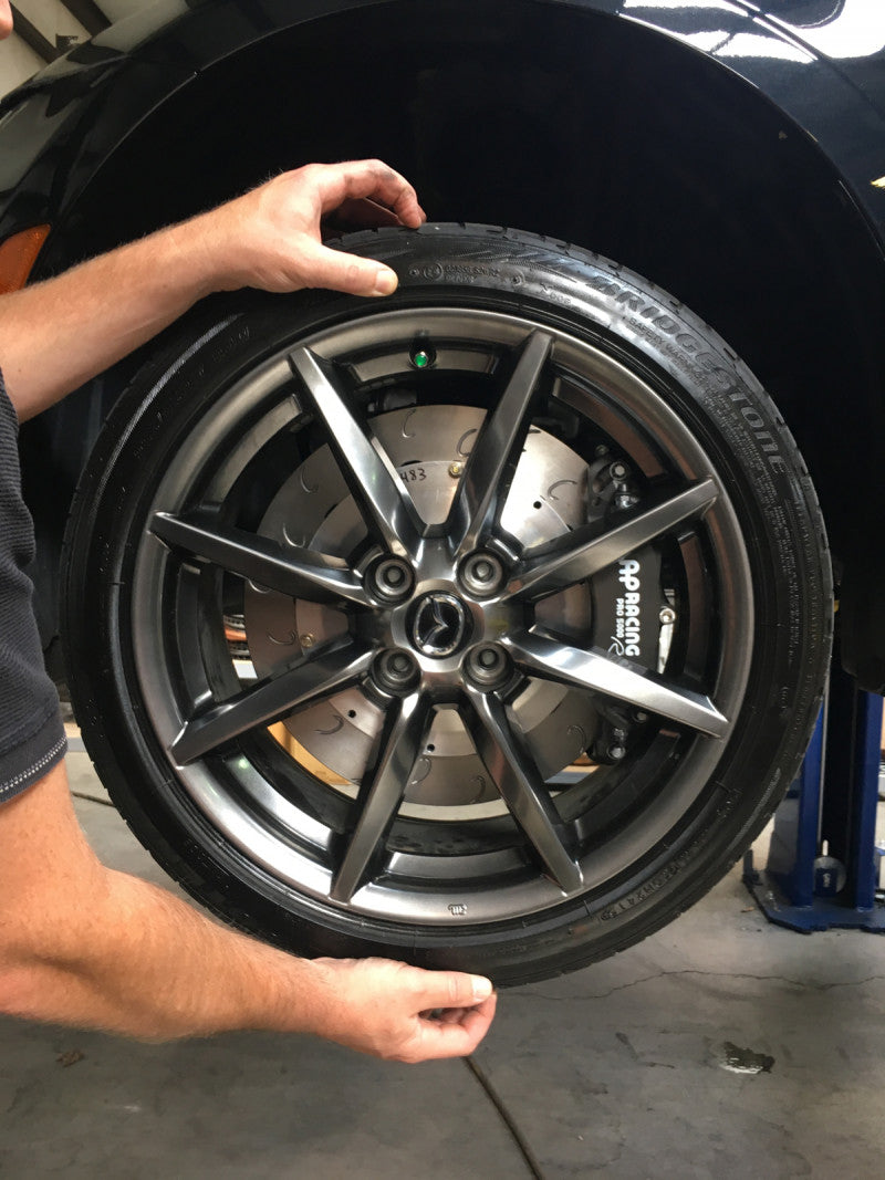 A close up view of a man holding a wheel fitted with AP Racing by Essex Radi-CAL ENP Competition Brake Kit (Front CP9449/340mm)- ND Mazda Miata & Fiat 124 Spider
