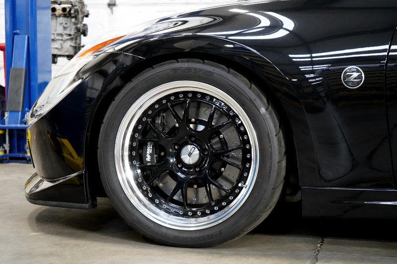 A close up view of a black Nissan and its wheel fitted with AP Racing by Essex Radi-CAL Competition Brake Kit (Front CP9660/372mm)