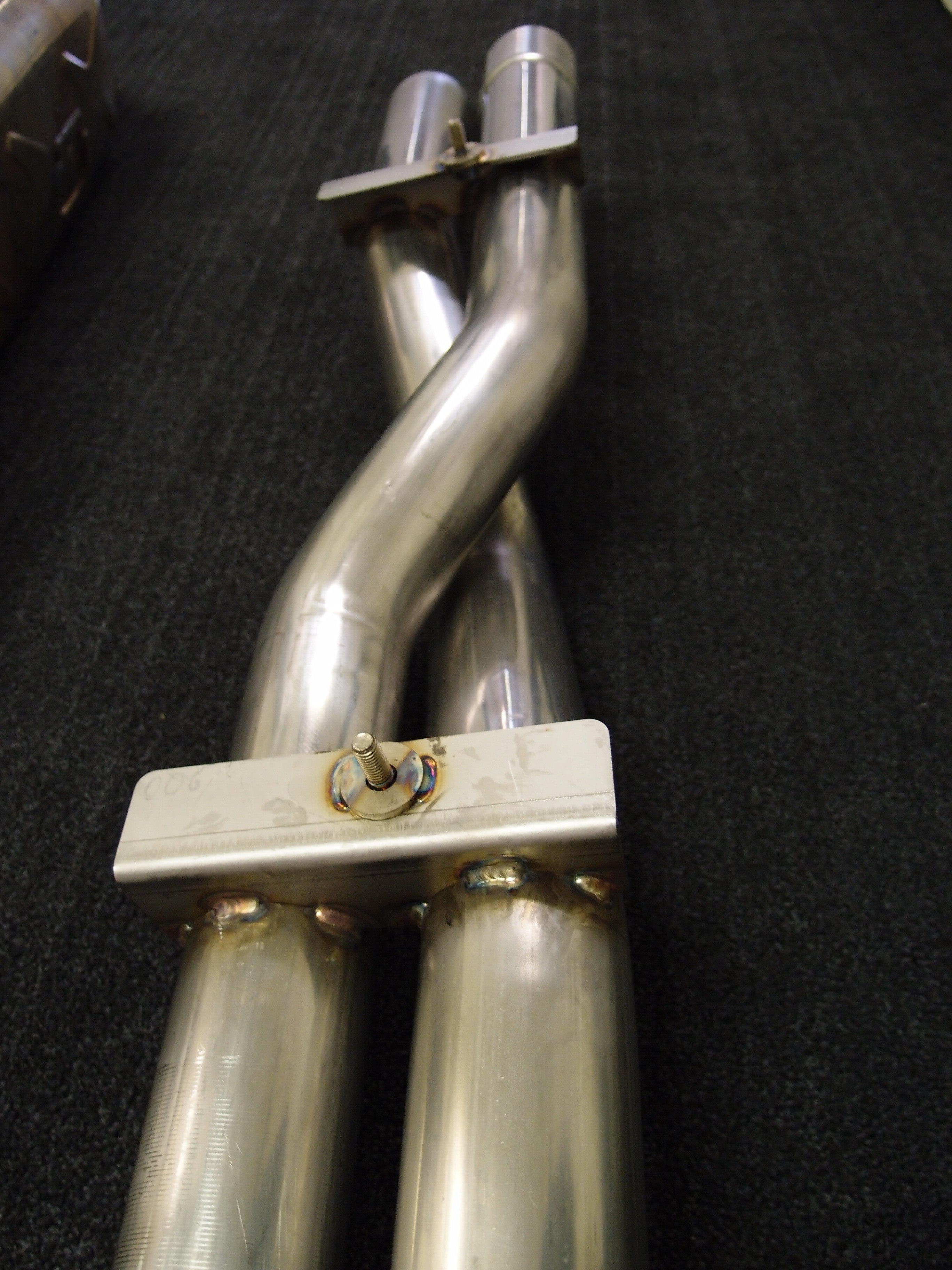 A wide view of Shark Werks Exhaust for Porsche 997.2 Turbo / S pipes on a black background