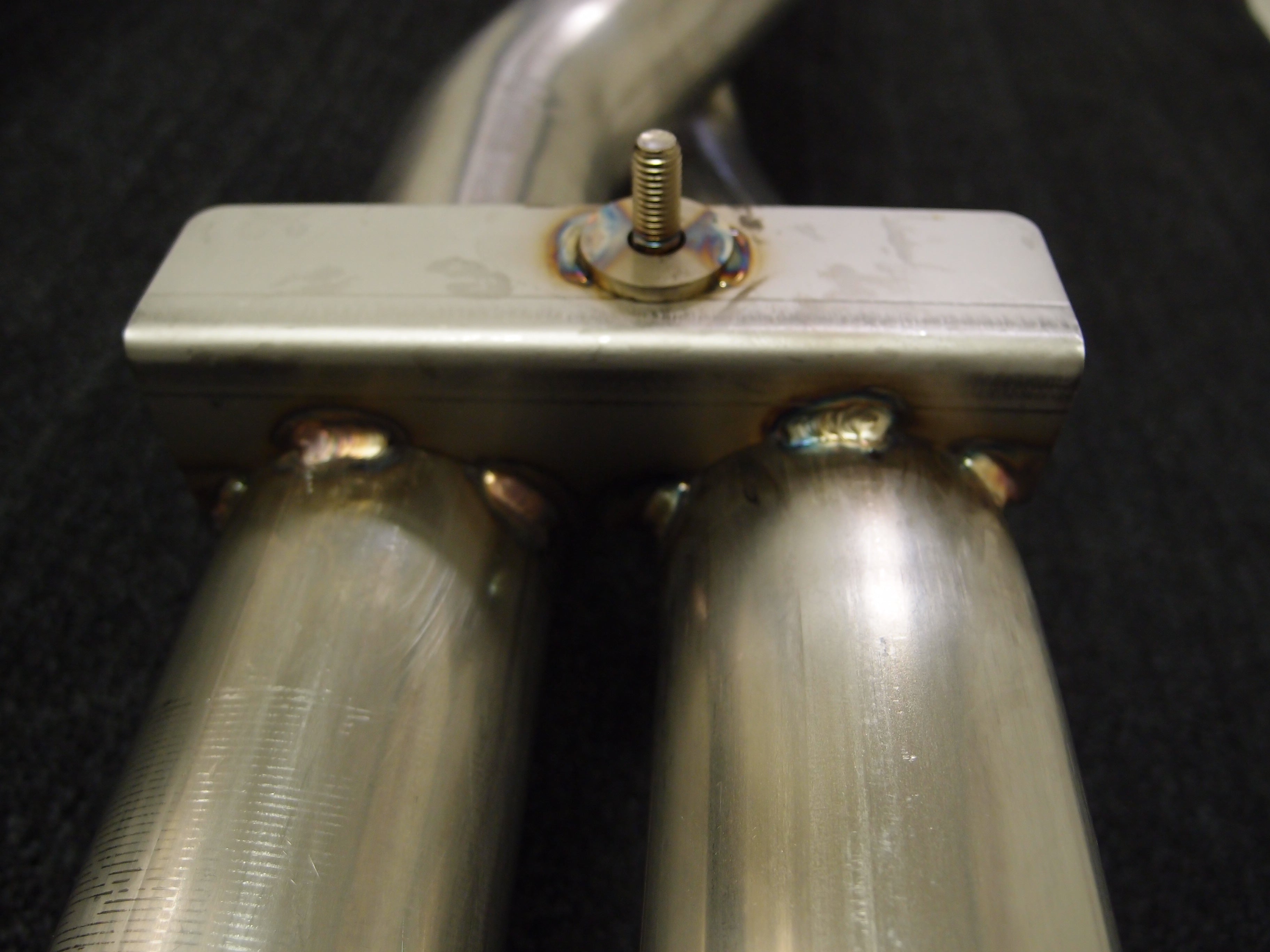 A close up view of Shark Werks Exhaust for Porsche 997.2 Turbo / S pipes with a black background