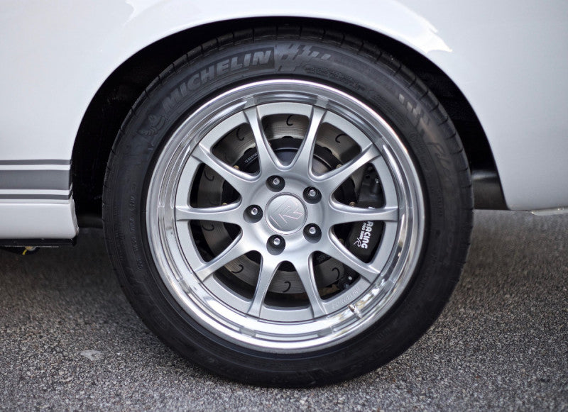 A close up view of a car's wheel fitted with P Racing by Essex Radi-CAL ENP Competition Brake Kit (Rear CP9449/340mm)- 9" Ford Custom Rear End Applications on the road